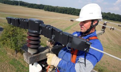 Im Bild ein Arbeiter auf einem Spannungsmast der Mitnetz Strom, für den Natzbetrieber steht die Digitalisierung der Mittel- und Niederspannungsnetze im Fokus.