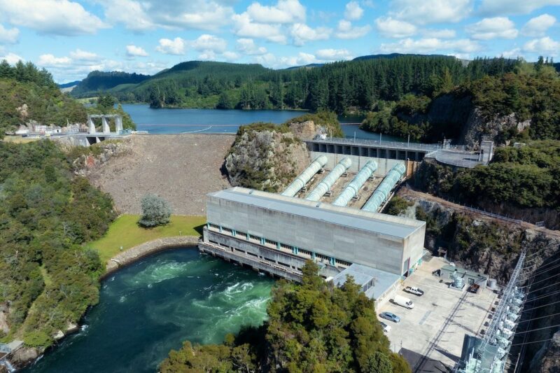 Das Foto zeigt ein Wasserkraftwerk in einer bewaldeten Hügellandschaft, dass einen Fluß in ein Oben und ein Unten teilt.