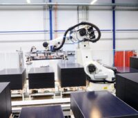 Ein Roboter stapelt schwarze Solarmodule.