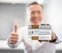 Person hält Smart-Meter-Gerät in der Hand mit Daumen hoch.