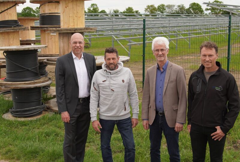 4 Personen auf einer Wiese mit installierten PV-Gestellen und Kabeln auf Trommeln.
