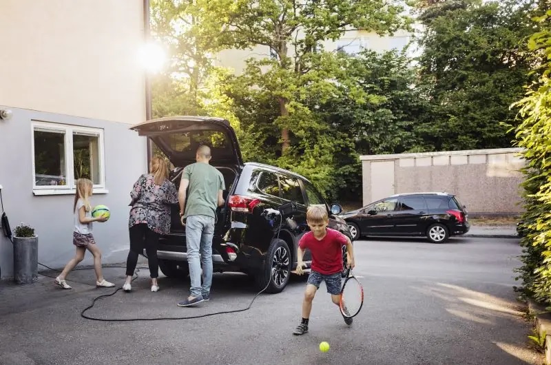 Zu sehen ist eine Familie mit E-Auto, die Netzintegration von Elektromobilität soll zugleich netzdienlich sein.