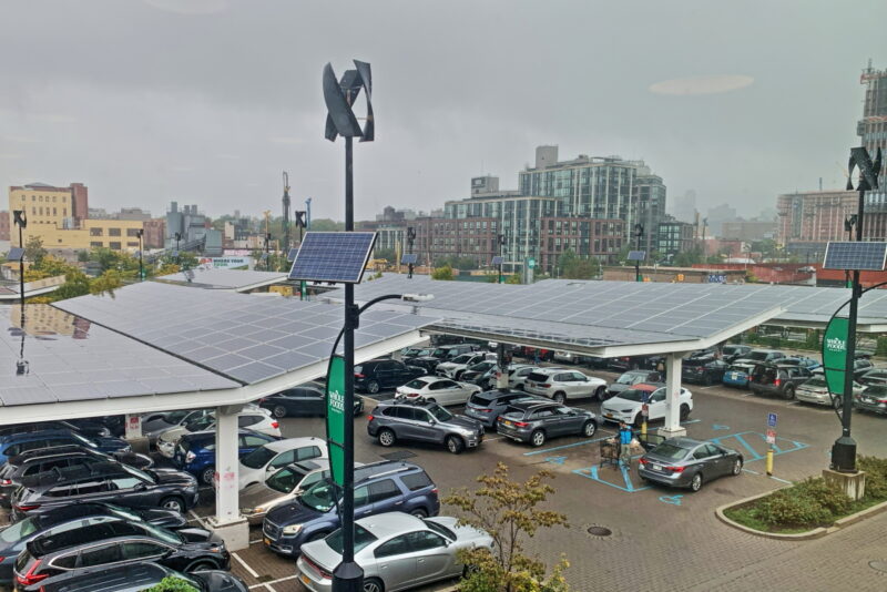 Parkplatz vor Supermarkt mit Photovoltaik in Brooklyn/New York. Im Hintergrund typische Hochhäuser.