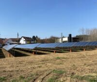 Mehrere Reihen von Solarkollektoren in dörflicher Umgebung.