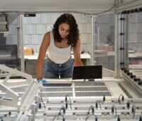Die Projektleiterin am Fraunhofer ISE, Najwa Abdel Latif kontrolliert die verschalteten Solarzellen am Schindel-Matrix-Stringer des Fraunhofer ISE.