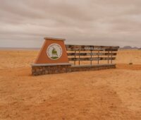 Flache Wüstenlandschaft mit Schild, das auf Nationalpark hinweist - Symbol für Wasserstoff- und Windenergiegewinnung in Namibia