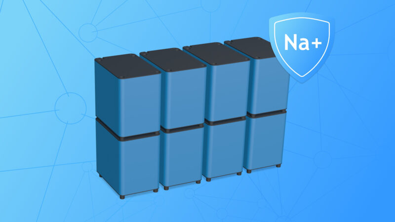 Computeranimation eines modular aufgebauten Heimspeichersystems mit acht blau-grauen Batteriemodulen vor blauem Hintergrund. Rechts daneben ist ein Schutzschild mit der Aufschrift „Na+“ als Hinweis auf die Natrium-Ionen-Technologie dargestellt.