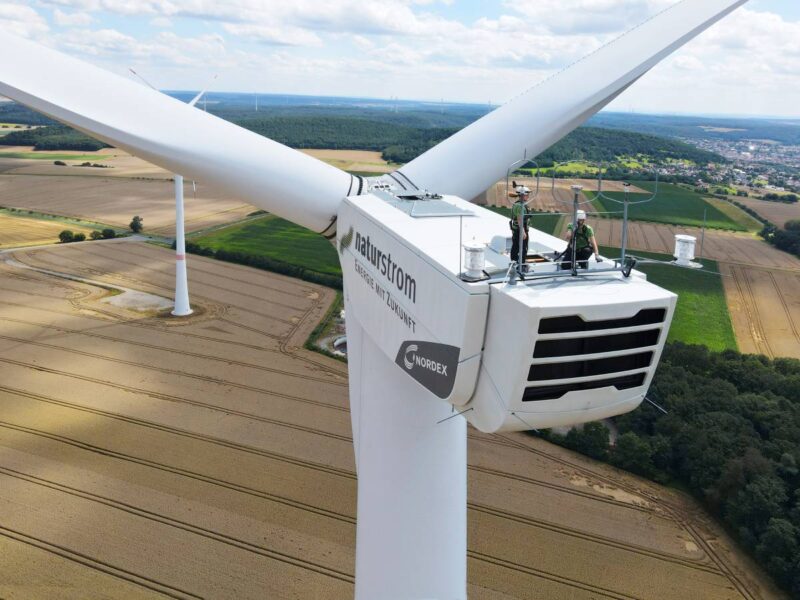 Zwei Mitarbeiter auf einer Gondel einer Naturstrom-Windanlage.