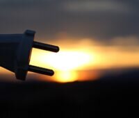 Im Bild ein Stecker vor Sonnenuntergang als Symbol für den Netzanschluss der Solaranlage.