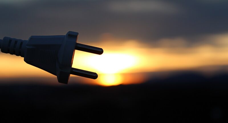 Im Bild ein Stecker vor Sonnenuntergang als Symbol für den Netzanschluss der Solaranlage.