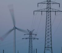 Rotierende Windmühle neben Strommasten