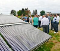 Besichtigung an der iKWK-SOlarthermie-Anlage in Lemgo: Gruppe steht im Kreis am Solarkollektorfeld