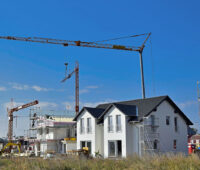 Neubaugebiet mit Doppelhäusern und Baukränen