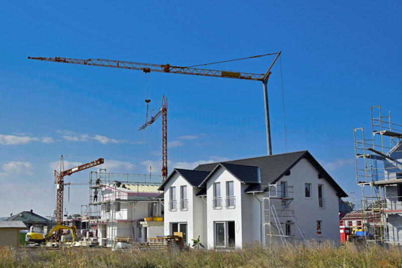 Neubaugebiet mit Doppelhäusern und Baukränen