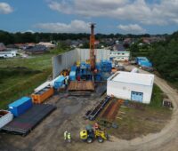 Luftbild einer Baustelle mit Geothermiebohrer und Containern.