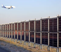 Senkrete Photovoltaikanlage von Next2Sun am Flughafen-Frankfurt. Darüber ein Passagierjet im Landeanflug