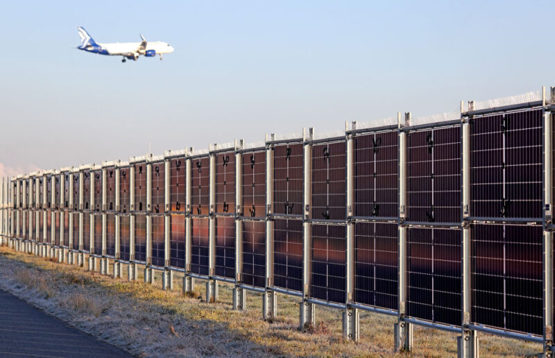 Senkrete Photovoltaikanlage von Next2Sun am Flughafen-Frankfurt. Darüber ein Passagierjet im Landeanflug