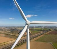 Blick auf die Nabe einer Windkraftanlage an Land. Im Hintergrund weitere Windkraftanlagen.