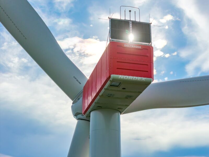 Gondel einer Windenergieanlage von Nordex gegen Sonne und leicht bewölktem Himmel.
