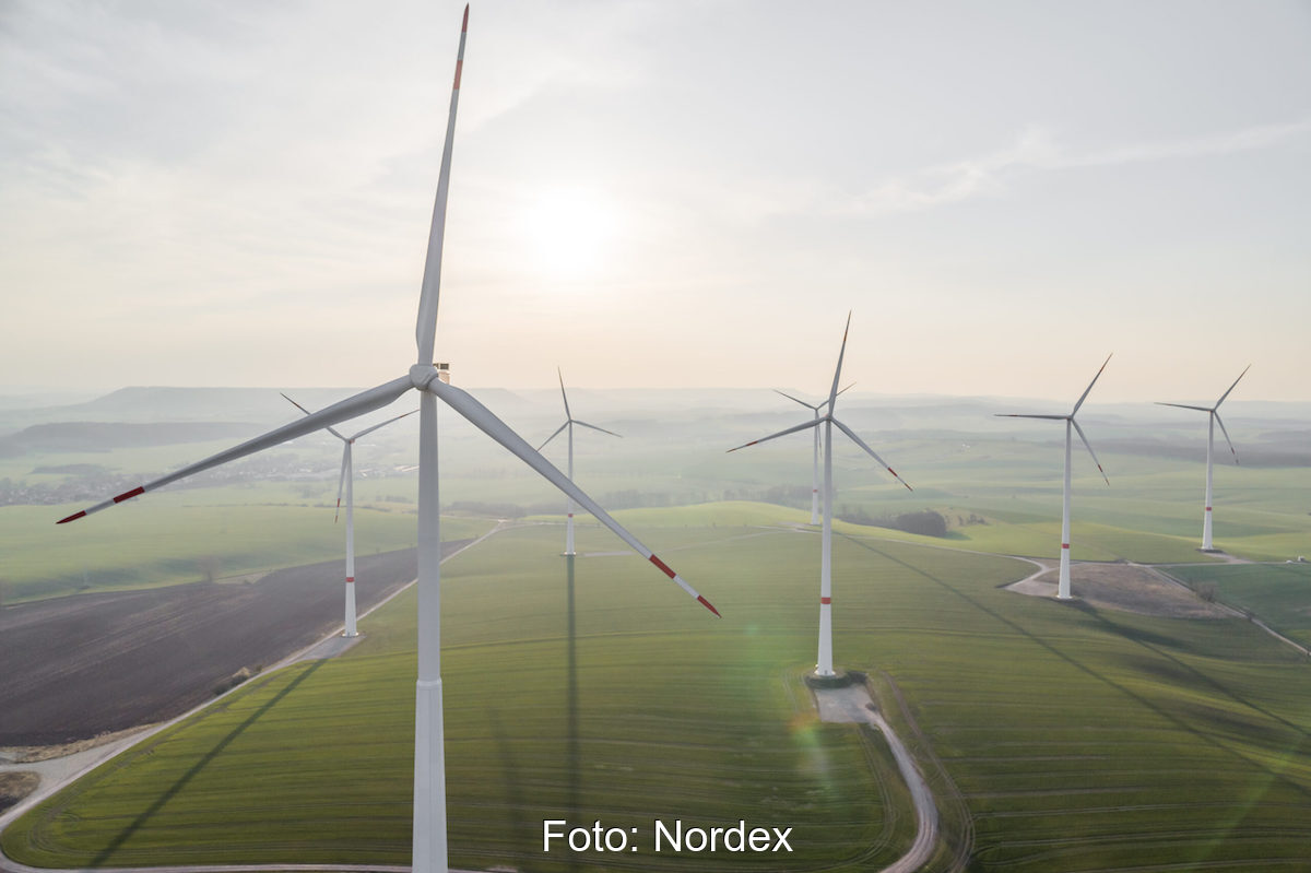 Mehrere Windkraftanlagen von Hersteller Nordex auf grünen Wiesen. Ein Abbild des europäischen Windmarkts.