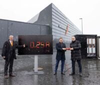 Der Personen mit großem Monitor und einem roten Stecker vor Messehallen in Nürnberg im Schneegestöber.