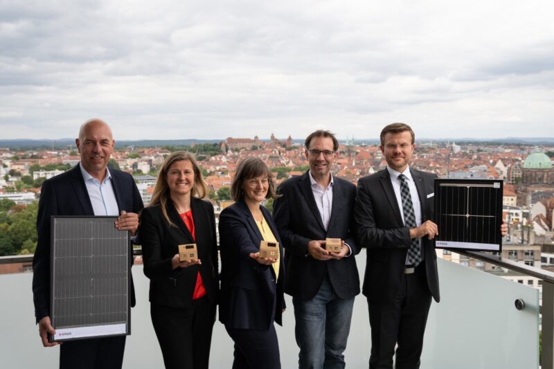 2 Frauen und drei Männer auf einem Hochhausdach mit Solarmodul
