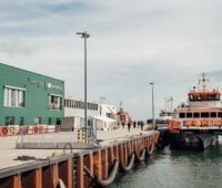 Kaikante mit grünem Gebäude mit der Aufschrift Wikinger an Land und Schiff im Wasser. Iberdrola kann bei seinen Offshore-Windparks in der Ostsee Synergien nutzen.