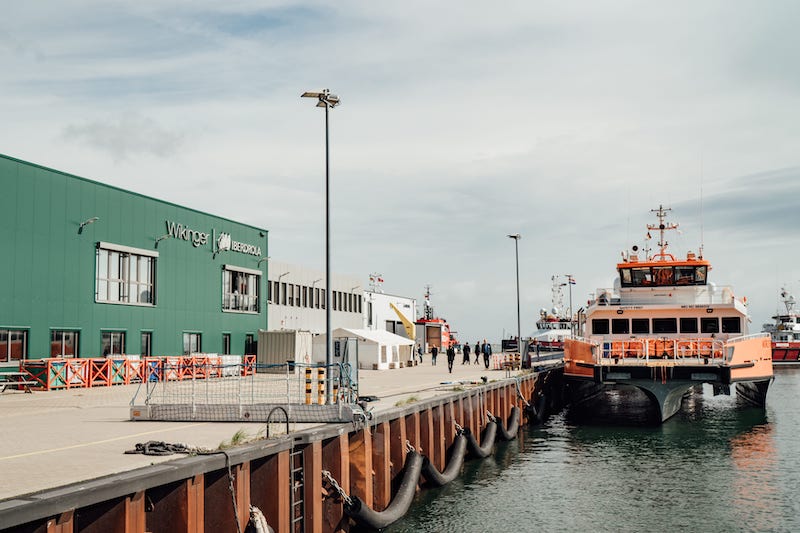 Kaikante mit grünem Gebäude mit der Aufschrift Wikinger an Land und Schiff im Wasser. Iberdrola kann bei seinen Offshore-Windparks in der Ostsee Synergien nutzen.