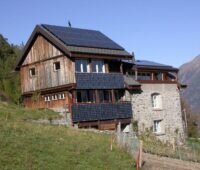 Zu sehen ist eine Berghütte mit PV auf dem Dach und an der Fassade. Die Einspeisetarifförderung für Photovoltaik-Dachanlagen in Österreich ist stark nachgefragt.