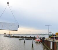 Im Bild ein Container am Haken über dem Wasser, der das Meerwasserlabor der BAM enthält.