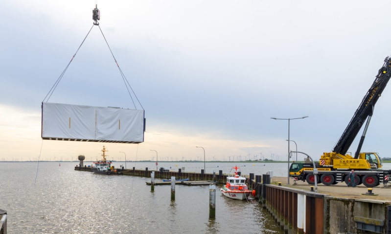 Im Bild ein Container am Haken über dem Wasser, der das Meerwasserlabor der BAM enthält.