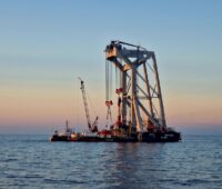 Kranartiges Gerüst auf dem Meer bei Sonnenuntergang - Fundamente setzen im Offshore Windpark Baltic Eagle