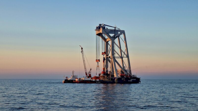 Kranartiges Gerüst auf dem Meer bei Sonnenuntergang - Fundamente setzen im Offshore Windpark Baltic Eagle