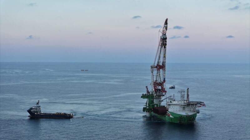 Ein Offshore-Installationsschiff mit großem Kran arbeitet auf ruhiger See an der Errichtung des Windparks Nordlicht I. Daneben liegt ein Versorgungsschiff; im Hintergrund ist die offene Nordsee zu sehen.