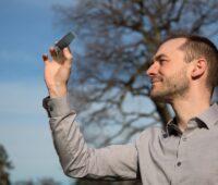 Ein Mann hält eine Solarzelle in die Höhe - semitransparente organische Photovoltaik in der Forschung.