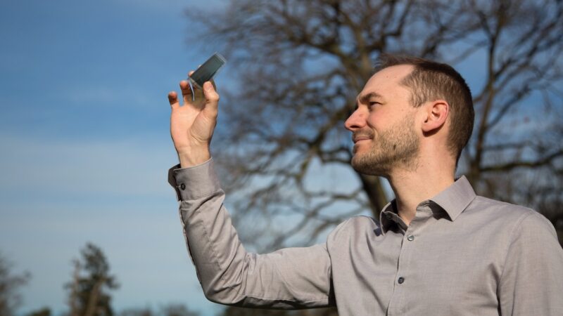 Ein Mann hält eine Solarzelle in die Höhe - semitransparente organische Photovoltaik in der Forschung.