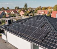 Haus mit schwarzem Schrägdach und Solarmodulen.