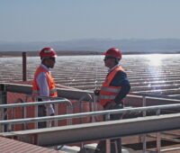 Zwei Ingenieure stehen in einem solarthermischen Spiegelfeld
