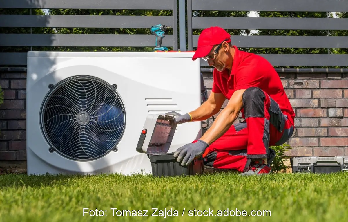 Links eine Wärmepumpe mit einem rot gekleideten, davor hockenden Heizungsmonteur als Symbolbild für flexible Wärmepumpen.