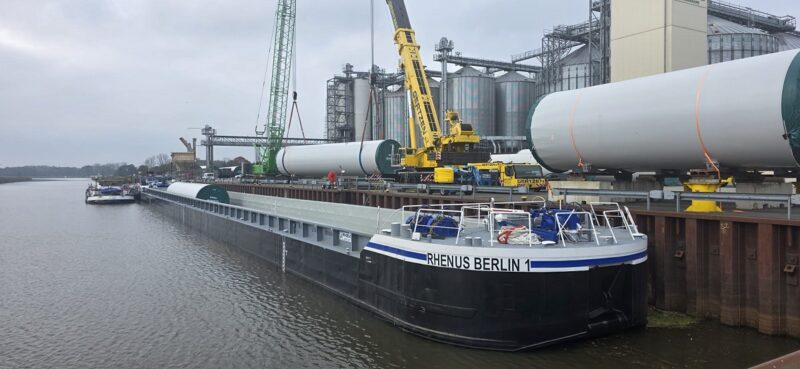 Ein Kran hebt die Stahlturmsektionen der Enercon-Windturbinen vom Schubleichter. Der Transport von Windturbinen-Komponenten auf Wasserwegen bietet Vorteile.