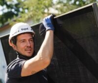 Im Bild ein Monteur mit Photovoltaik-Modul auf der Schulter, Enpal hat 2025 den Umsatz mit Photovoltaik und Wärmepumpen gesteigert.