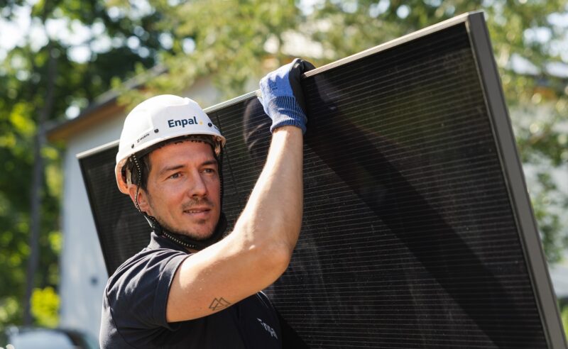 Im Bild ein Monteur mit Photovoltaik-Modul auf der Schulter, Enpal hat 2025 den Umsatz mit Photovoltaik und Wärmepumpen gesteigert.
