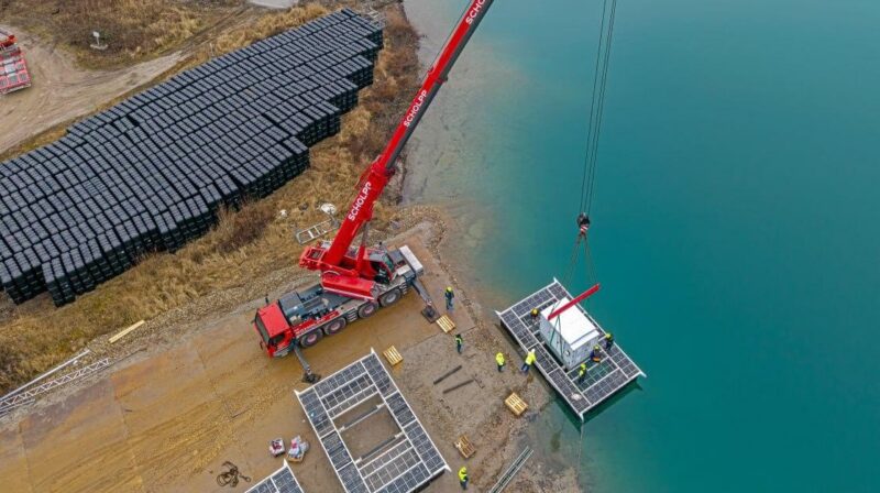 Ein Kran hievt einen Container auf eine künstliche Insel, Bauarbeiten für die schwimmende Solaranlage (Floating-PV) auf dem Kühlsee in Iffezheim.