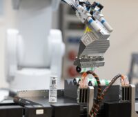 Im Bild ein Batterien, die ein Maschinenarm ablegt, das Fraunhofer IPA hat Batterien mit Aluminium-Anode entwickelt.