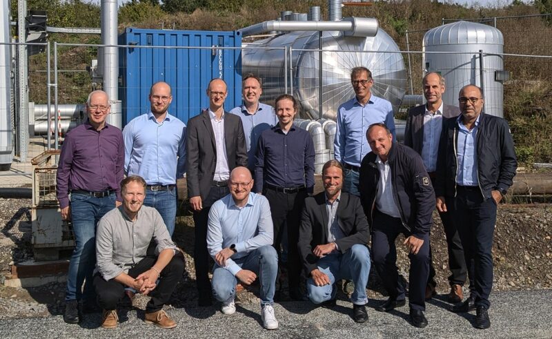 Menschen vor eine Energieanlage beim Kick-off-Treffen des Projektes Biovolatil, das kommunale Energiesysteme stärken will.