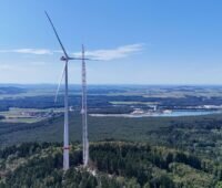 Ein Kran neben einer Windenergieanlage (WEA), Die höchste Serien-Windenergieanlage der Welt hat eine Weltrekord-Nabenhöhe von 199 Metern Max Bögl präsentiert sie auf der WindEnergy Hamburg 2026.