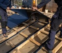 Zwei Installateure auf dem Dach montieren das Level Up Photovoltaik-System für die Dachintegration von Megasol.