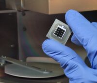 Hand mit Handschuh hält die von einem Photovoltaik-Forschungsteam der LMU erzeugte Perowskit-Silizium-Tandemzelle mit verbesserter Passivierung.