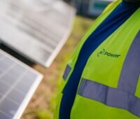 Ein Mann mit gelber Weste mit Aufschrift R.Power vor Photovoltaik-Modulen, das Unternehmen hat sich 115,5 MW in EEG-Innovationsausschreibung gesichert.