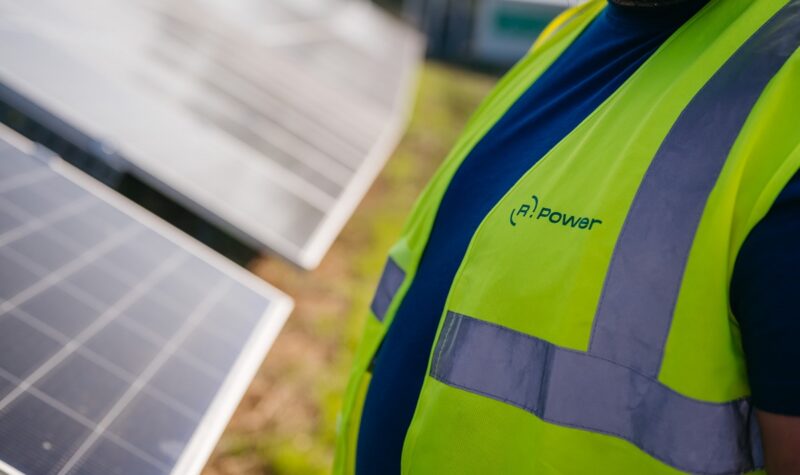 Ein Mann mit gelber Weste mit Aufschrift R.Power vor Photovoltaik-Modulen, das Unternehmen hat sich 115,5 MW in EEG-Innovationsausschreibung gesichert.